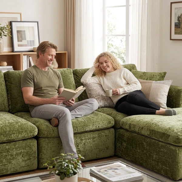 Two people relaxing with a book and a mug on a green sofa